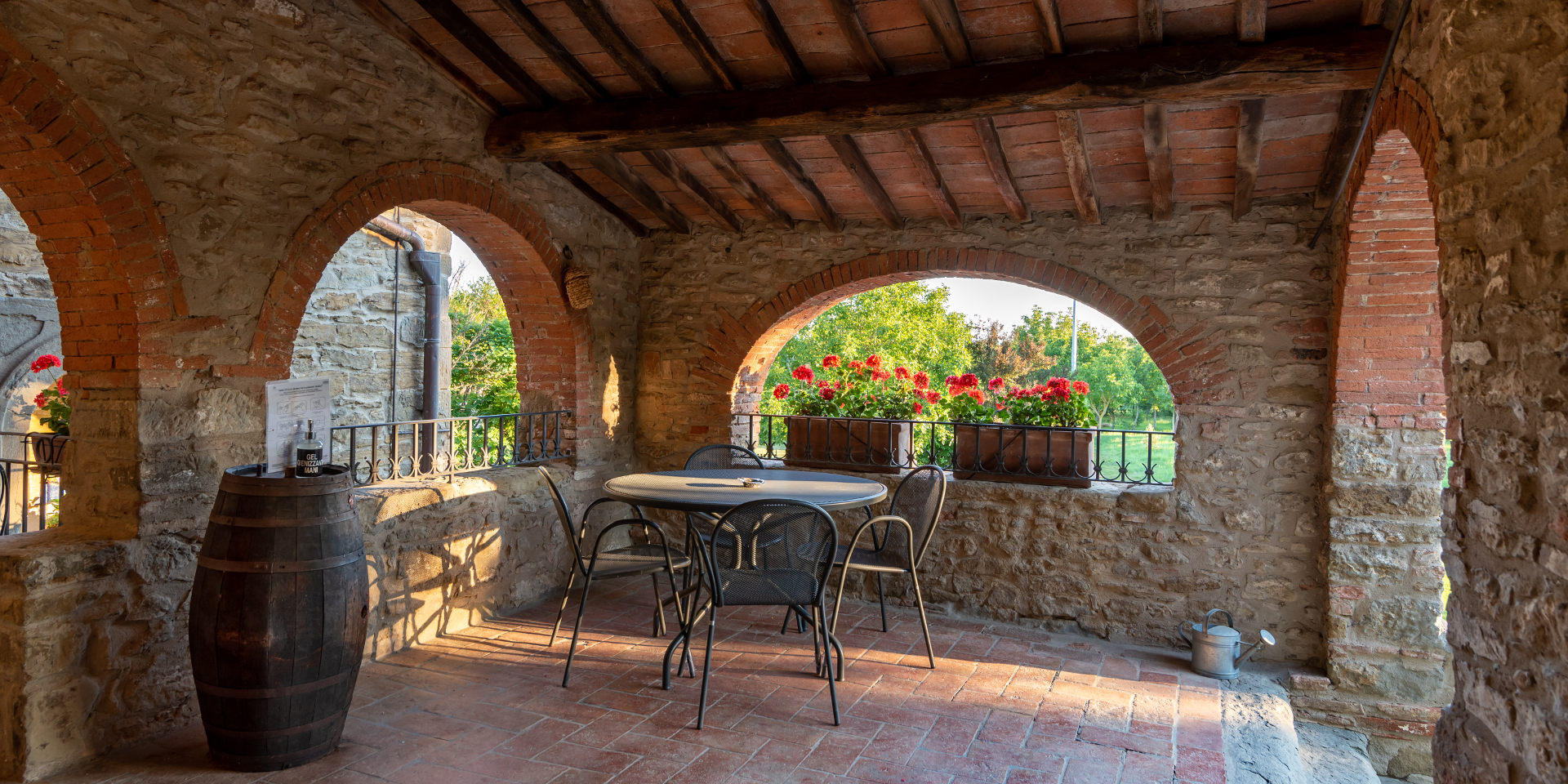 Agriturismo Monastero San Silvestro, un tavolo con delle sedie
					all’ombra di un porticato